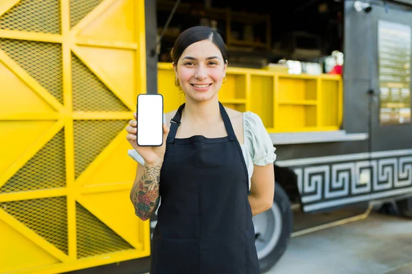 ファーストフードトラックで働いている間に配達アプリから注文を受けている美しい女性ベンダー — ストック写真