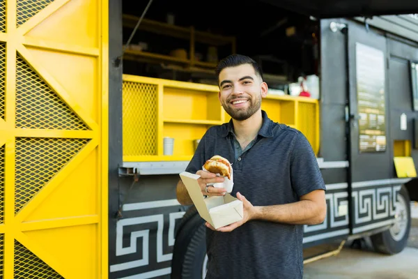 彼の昼食の注文を受けて 食品トラックからサンドイッチを食べる準備ができている陽気な若い男 — ストック写真
