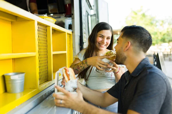 笑顔のカップル笑って楽しいしながら食べ物トラックでおいしいサンドイッチを食べて — ストック写真