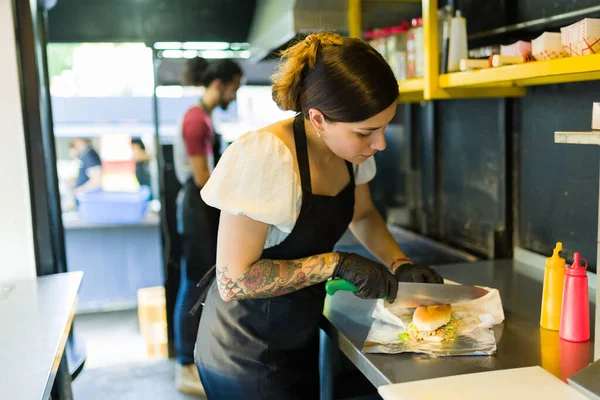 Hispanic female cook ready to serve a sandwich for diners of her fast food truck