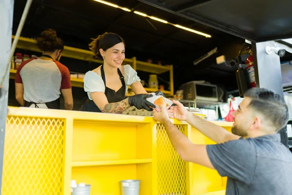 ファーストフードトラックで昼食を購入する顧客にサンドイッチを提供する陽気な屋台のベンダー — ストック写真