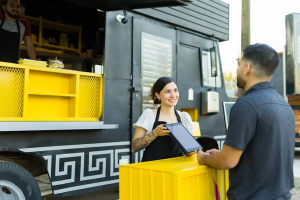 食品トラックの顧客にファーストフードメニューを示す陽気な労働者と屋台のベンダー — ストック写真