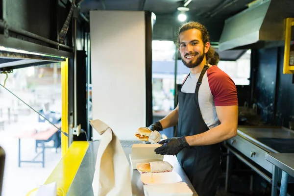 Happy mexican cook finishing preparing sandwiches at the food truck