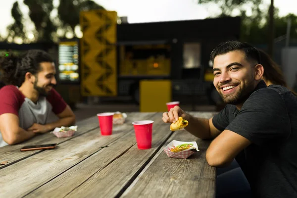 陽気なハンサムなラテン人おいしいメキシコ料理を食べると食べ物のカートからタコスを食べる — ストック写真