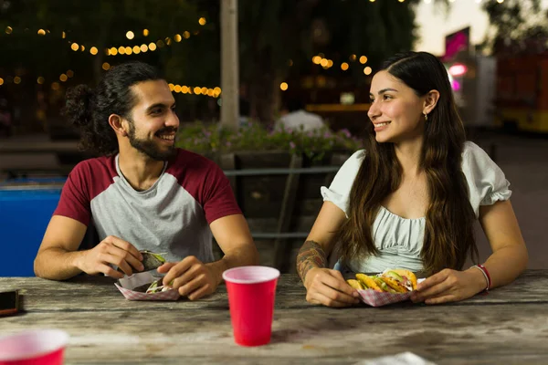 快乐而美丽的女人和男人一边笑着一边吃着从餐车上买来的墨西哥玉米卷 — 图库照片