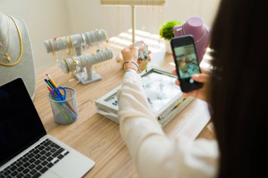 Çevrimiçi mağazası için akıllı telefonuyla fotoğraf çeken bir girişimcinin arka görüntüsü