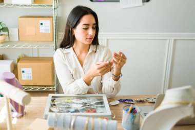 Online satıcı kadın envanter çıkarıyor ve online dükkanının mücevherlerine bakıyor.