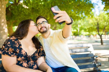 Birlikte selfie çekerken koca kız arkadaşını yanağından öpmek.