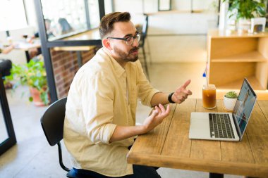 Kafeteryada çalışan beyaz bir adamın profili ve bilgisayarında video kaydı var.