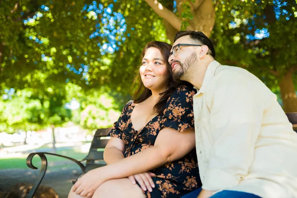 リラックスしたラテン脂肪の女性と原因アジアの男抱擁でザ ベンチと愛のあるデートで公園 — ストック写真