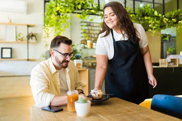 微笑的女服务员带着松饼和咖啡到咖啡店给快乐的男性顾客 — 图库照片