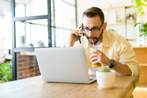 Homem Ocupado Bebendo Café Gelado Enquanto Falava Telefone Digitando Laptop — Fotografia de Stock