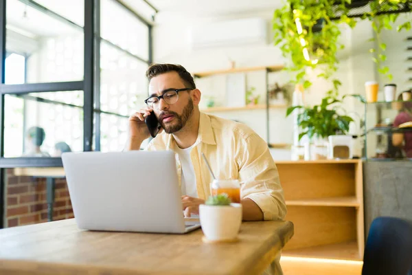 Kahve Dükkanında Dizüstü Bilgisayarla Çalışırken Müşteriyle Telefonda Konuşan Profesyonel Bir — Stok fotoğraf