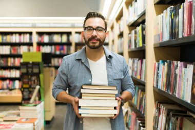 Kitapçıda alışveriş yaparken yanında bir sürü kitap taşıyan mutlu çekici bir adam. 