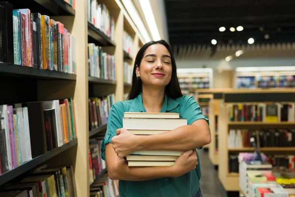 兴奋的拉丁女人在书店买小说的时候带着很多书看起来很开心 — 图库照片