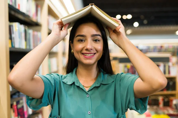 本屋で遊んだり本を読んだりしながら遊ぶ遊び心のある若い女性 — ストック写真