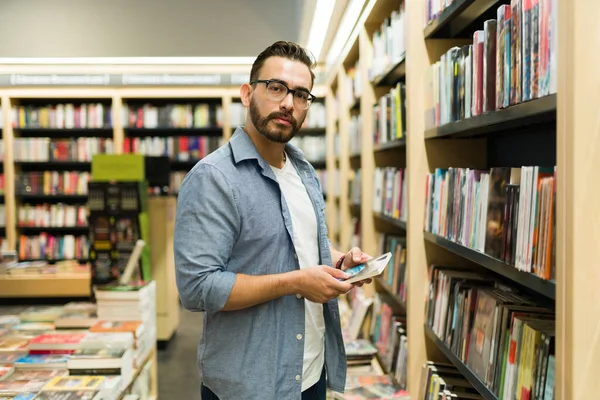 一个英俊的高加索男人在书店买书和买小说的画像 — 图库照片