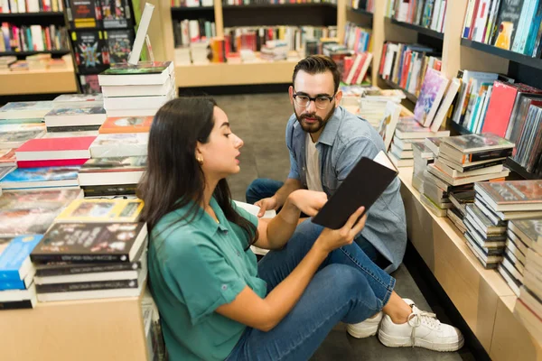 聪明的年轻女人在书店一起购物的时候大声给一个高加索男人读一本书 — 图库照片
