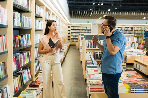 书店的一位愤怒的年轻女士向一位在电话中大声说话的男性顾客要求安静 — 图库照片