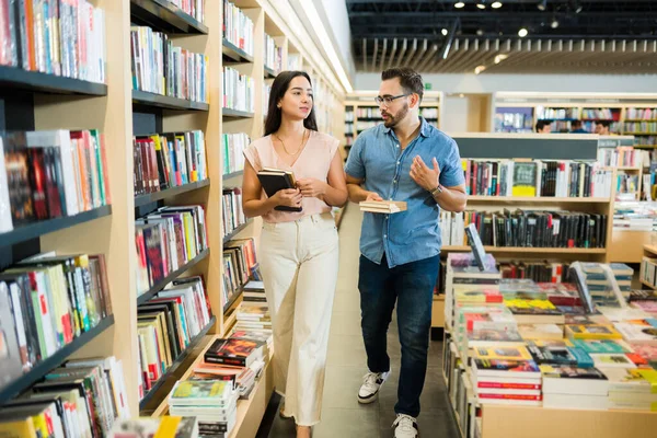 迷人而快乐的夫妻一边散步一边在书店聊天 一边一起买书 — 图库照片