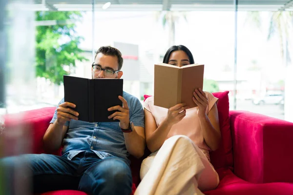 聪明的年轻女人和男人在沙发上休息 一起看书 — 图库照片