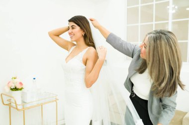 Mutlu anne dükkanda güzel bir gelinlik denerken kızına peçe takıyor.