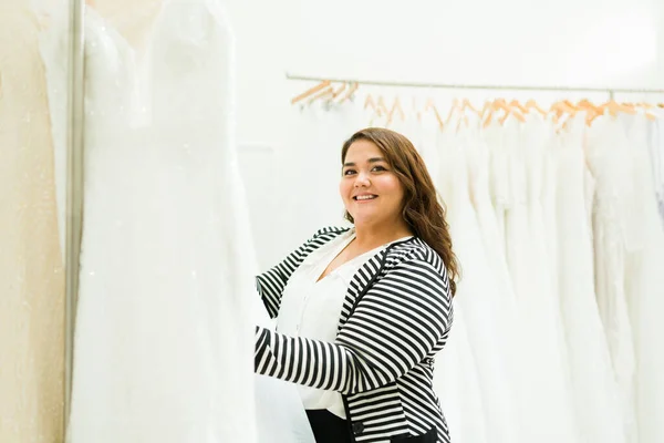 Portrait of a latin chubby woman and future bride looking at the camera while buying a beautiful wedding dress