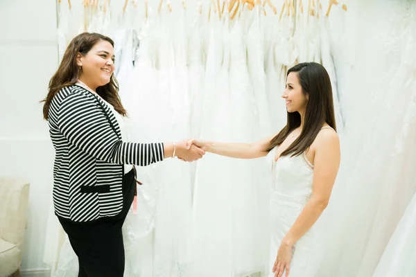 Uśmiechnięta Młoda Kobieta Uściska Dłoń Sprzedawcy Kupując Suknię Ślubną Sklepie — Zdjęcie stockowe
