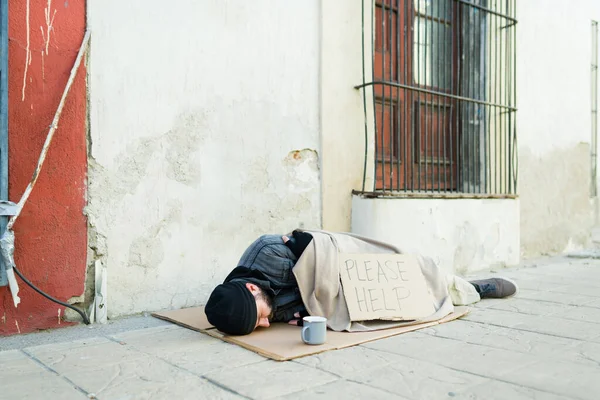 冷冰冰的乞丐流浪汉 裹着毛毯睡在街上 上面有一张纸牌 请帮我签个名 — 图库照片