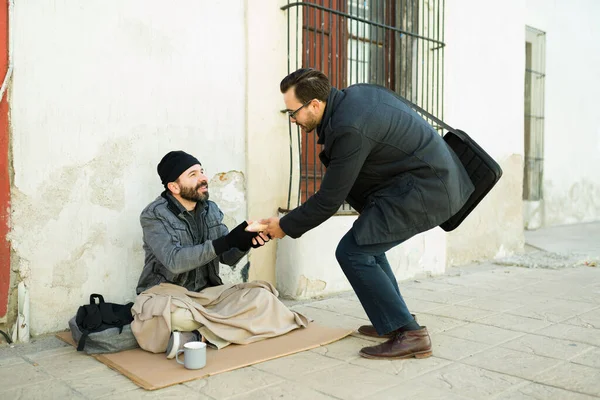 路上生活の幸せなホームレスの男に食べ物を与える慈善の優しさをやっている若い男 — ストック写真