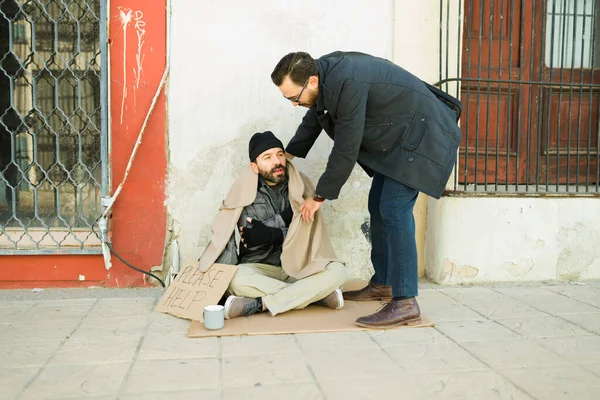 Troskliwy Miły Człowiek Oddaje Swoją Kurtkę Zimnemu Nędznemu Bezdomnemu Cierpiącemu — Zdjęcie stockowe