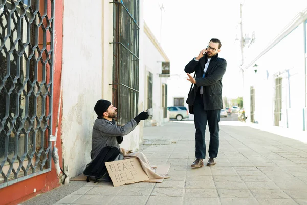 路上でお金を求めて苦労ホームレス乞食にノーと怒っている若い男を見て動揺 — ストック写真