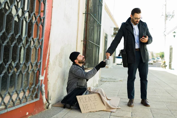 Homeless man saying thank you to a distracted caucasian man giving money for food