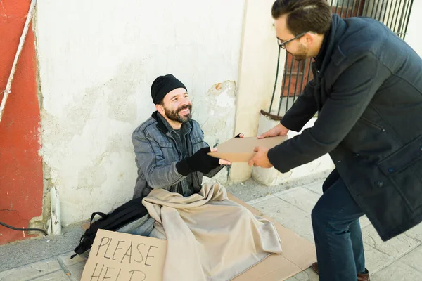 在街上挣扎的快乐的无家可归的人一边微笑着 一边接受一个善良男人的礼物 — 图库照片