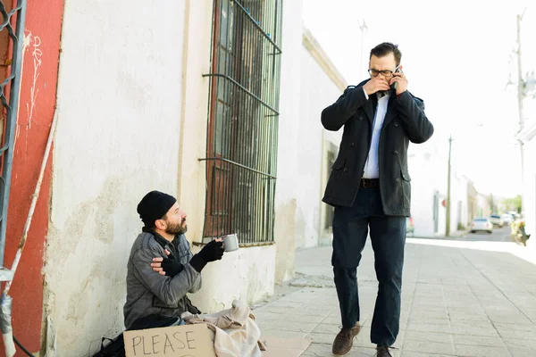 通りで苦しんでいる汚れた臭いホームレスの男の隣を歩いている間 彼の鼻と口を覆う白人男性 — ストック写真