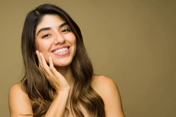 Onnellinen Latino Nainen Katselee Kameraa Koskettaessaan Hänen Sileä Iho Tunne — kuvapankkivalokuva