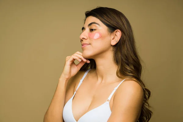 若いラテン女性使用してブラジャーとアイマスク間に彼女のスキンケアルーチンのための健康な肌 — ストック写真