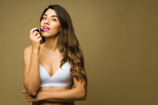20多岁的墨西哥美女在工作室的背景下涂上粉红口红和化妆品 — 图库照片