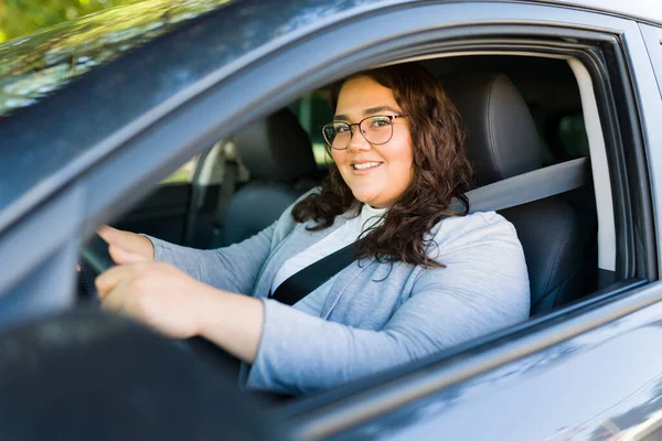 彼女の車を運転しながら 仕事に通勤しながら 美しいラテン語の女性は幸せそうに見て笑って目の接触を作ります — ストック写真