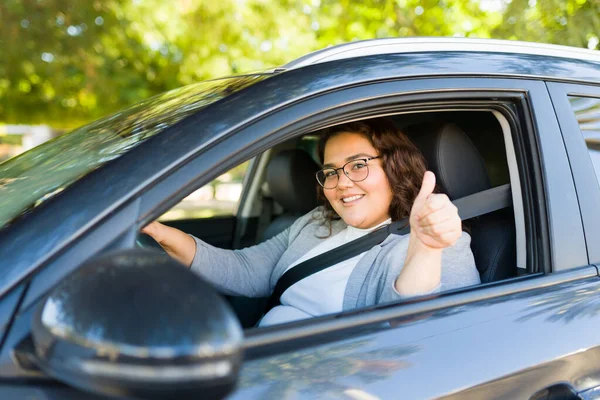幸せな太りすぎの女の肖像画作る目の接触笑顔ショーA親指アップしながら運転彼女の優れた車 — ストック写真