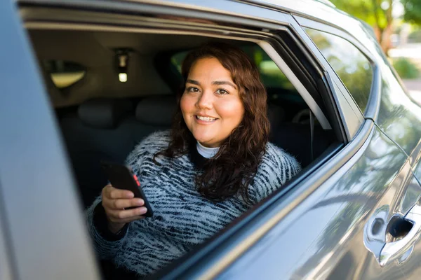 乗車中に笑顔で陽気な肥満女性の乗客シェアカーに旅行し スマートフォンやテキストメッセージでアプリを使用して — ストック写真