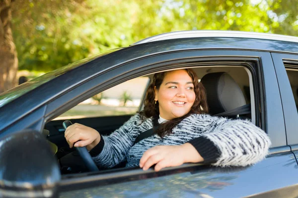 Beautiful obese woman looking out the car window while driving and looking happy
