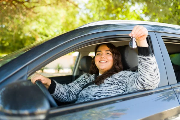 新しい車を購入した後 運転しながら笑顔とキーを示す興奮した脂肪の女性の肖像画 — ストック写真