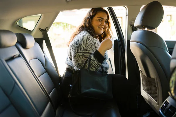 Smiling obese woman taking a trip using a rideshare app while making eye contact