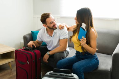 Birlikte tatile çıkmaya hazırlanırken bavullarını ve pasaportlarını kullanarak gülümseyen güzel bir çift.