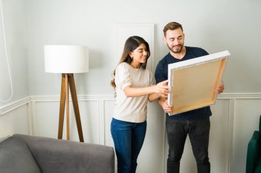 Çekici çift gülümserken yeni evlerinde resim süslemeleri yapıyorlar.