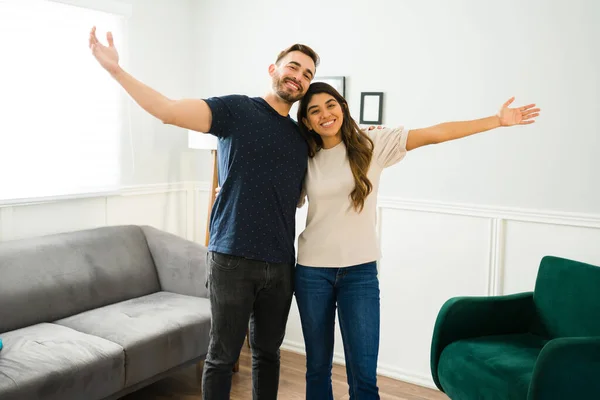 Excited couple opening their arms and looking very happy about moving in together to a new home