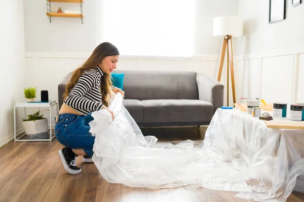 若い女性のプロフィール自宅でプロジェクトや趣味を反転彼女の家具の作業を開始するには プラスチックシートを置く — ストック写真