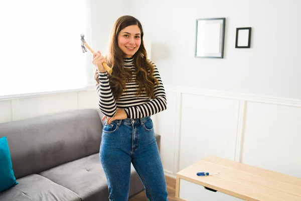 Cheerful attractive woman using a hammer while doing DIY projects and assembling furniture