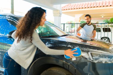 Meksikalı çift garajlarında birlikte ev işi yaparken arabalarını süngerle temizliyor.
